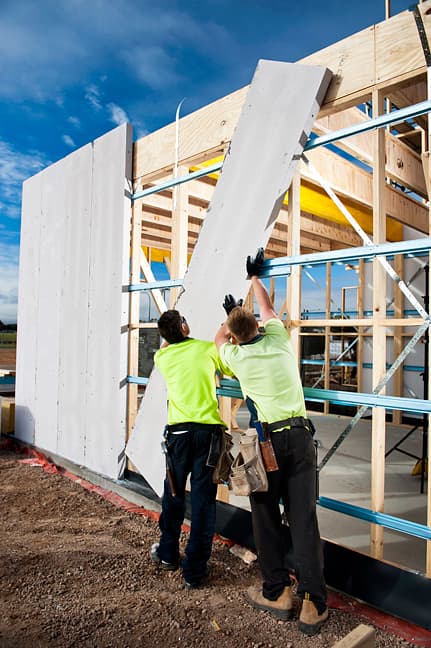 MYT installers lifting an AAC panel into place on a residential wall frame