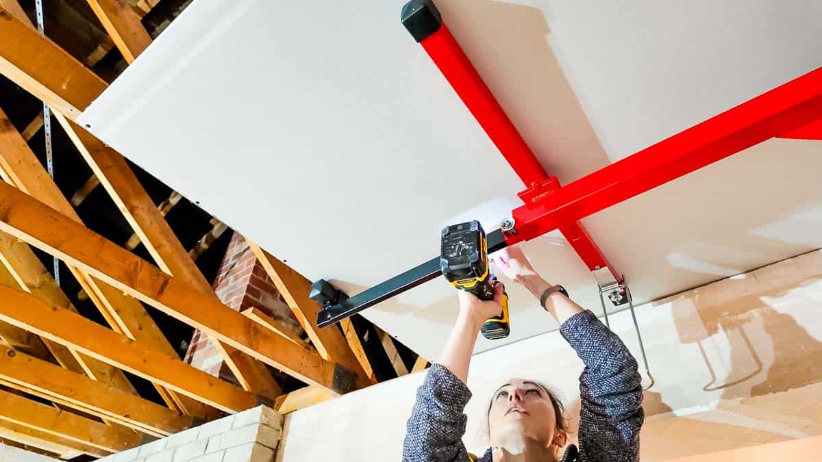 Installer fixing a plasterboard ceiling sheet with a panel lifter