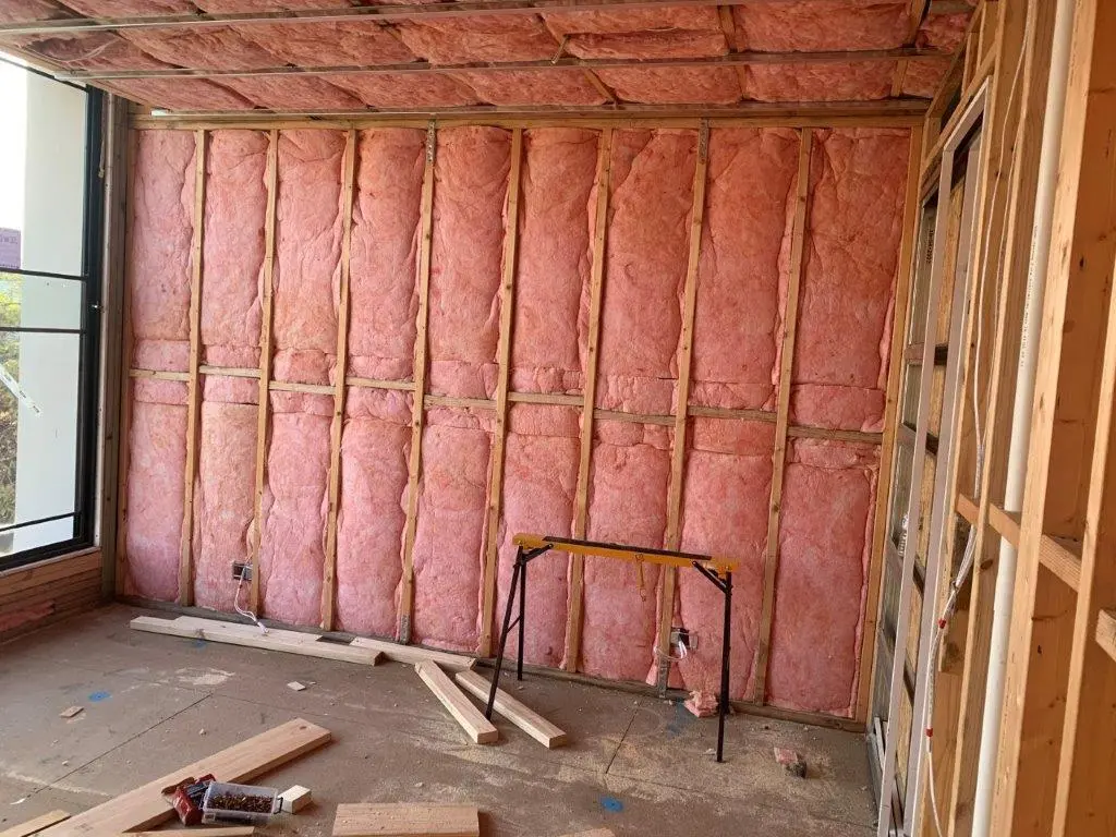 Wall insulation batts installed through a timber stud frame before lining